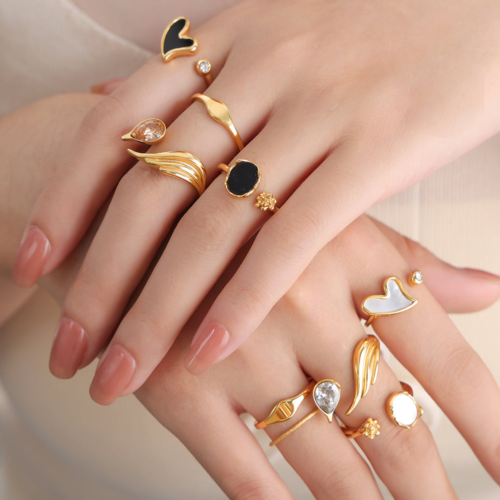 Close-up of a hand wearing multiple gold rings with various designs on a neutral background