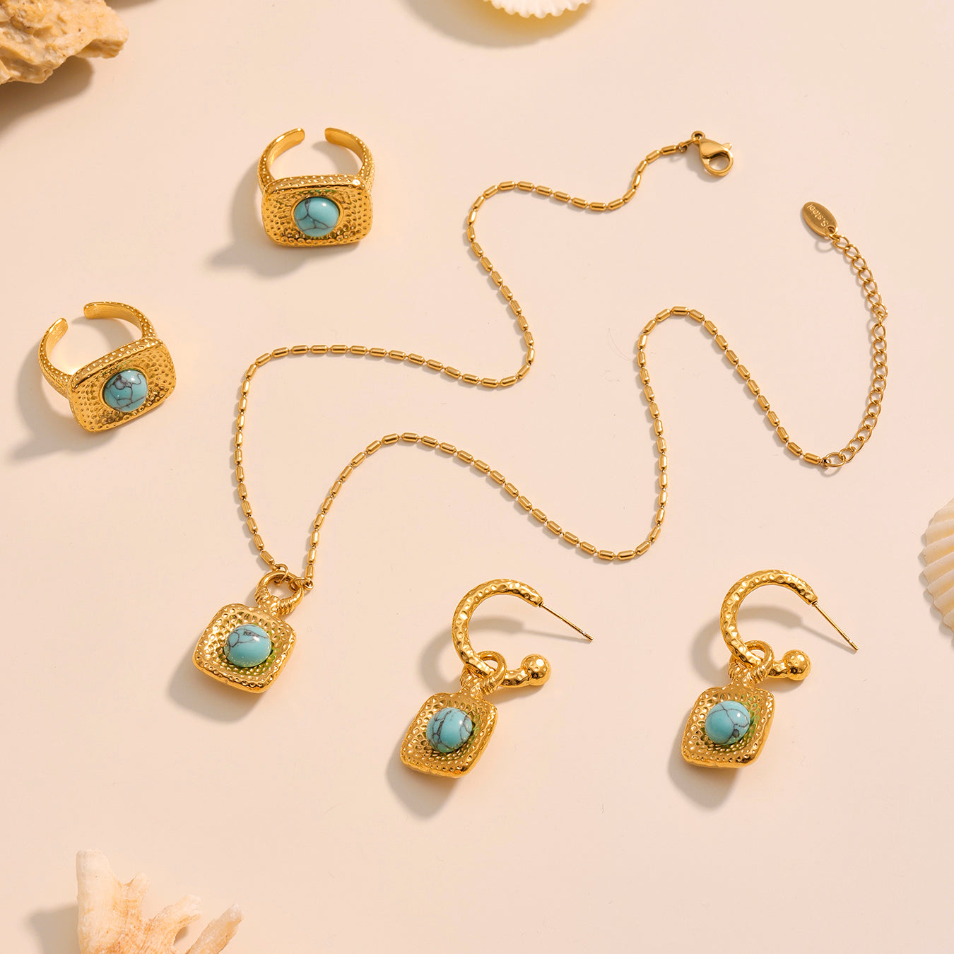 Gold jewelry set with turquoise stones on a beige background