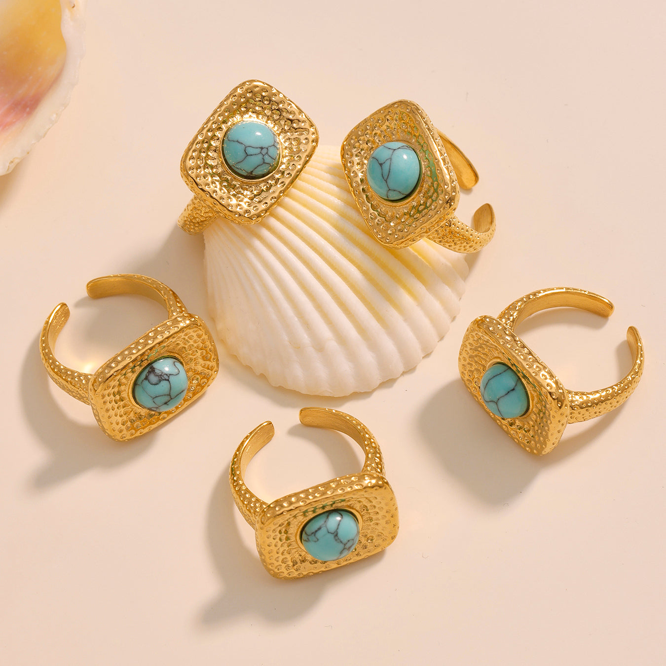 Set of gold rings with turquoise stones on a beige background