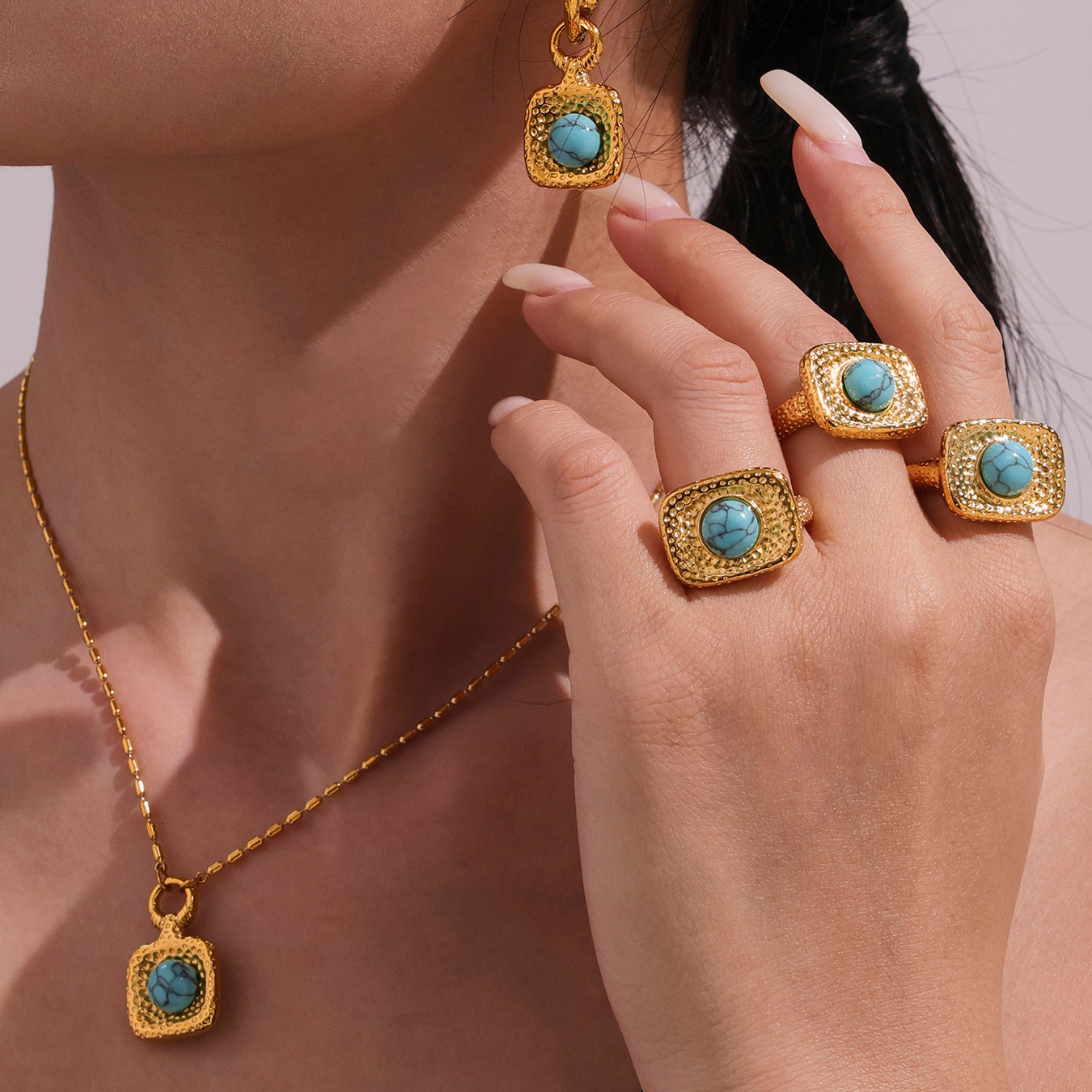 Gold jewelry set with turquoise stones on a neutral background