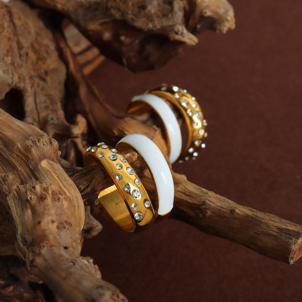 Gold and white earrings on a wooden surface