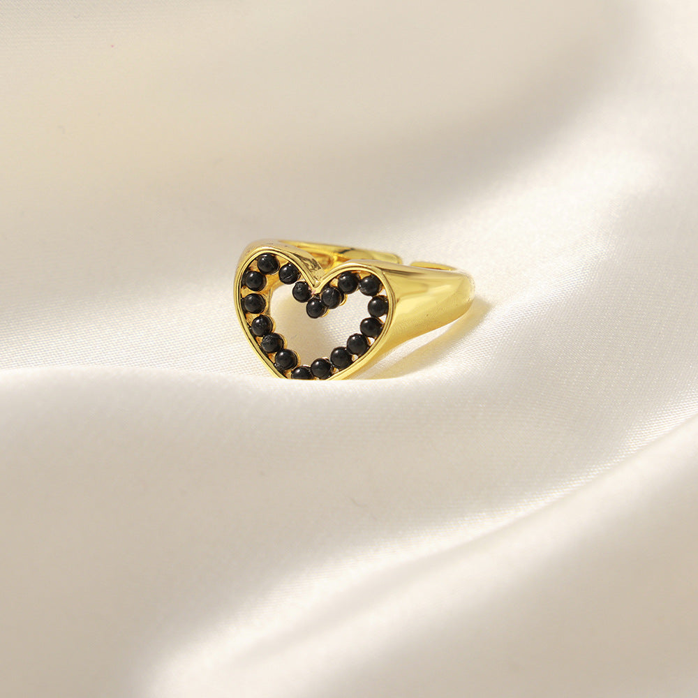 Gold ring with black gemstones on a light beige background