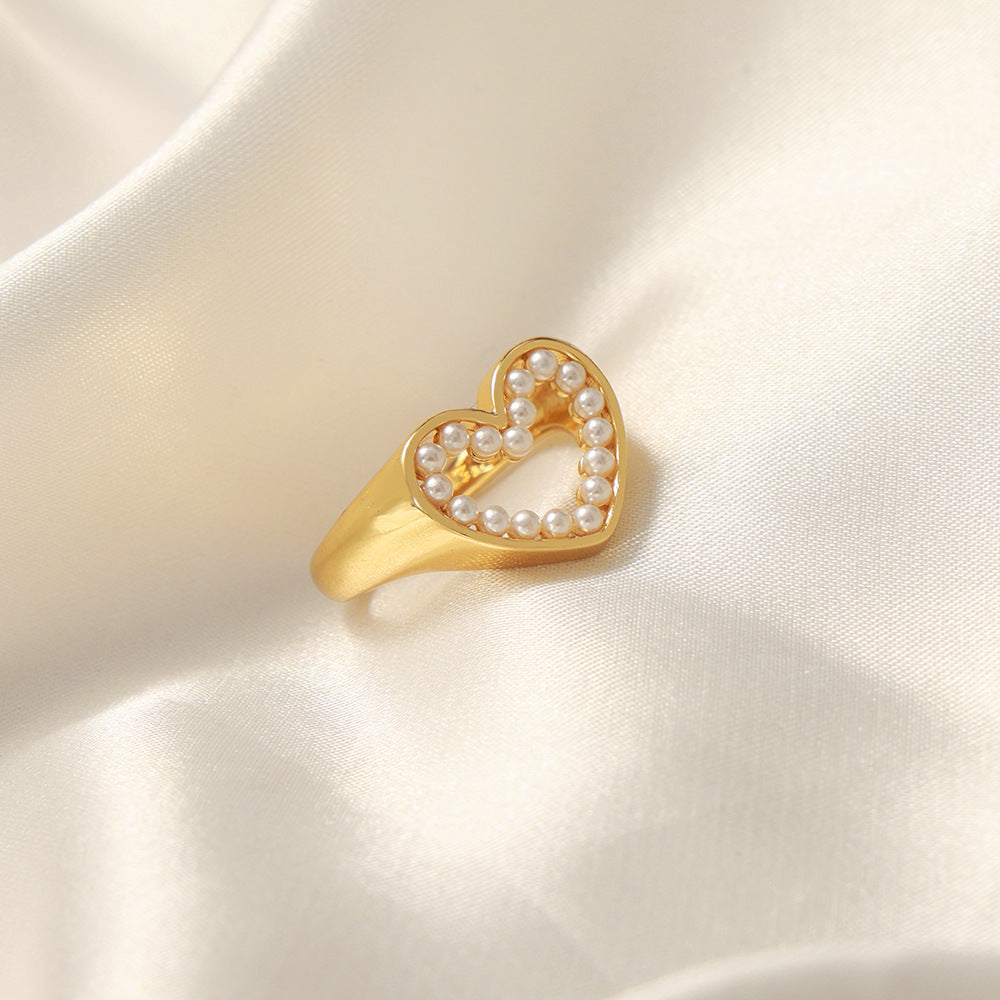 Gold heart-shaped ring with pearls on a satin background
