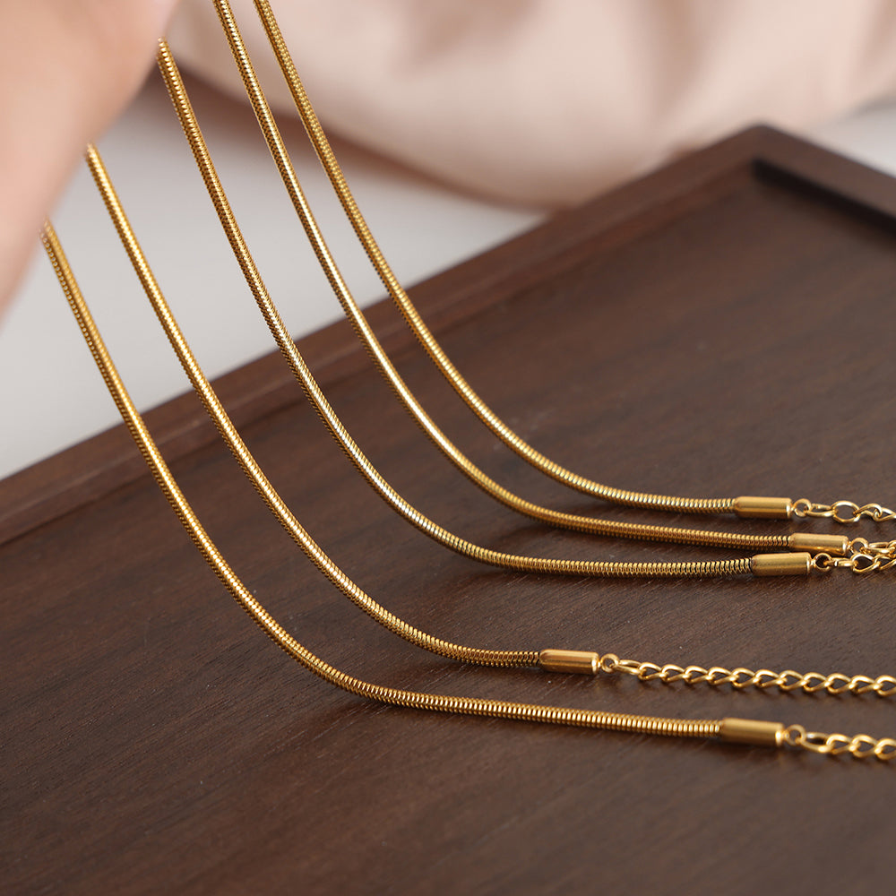 Gold necklaces of different lengths on a wooden surface