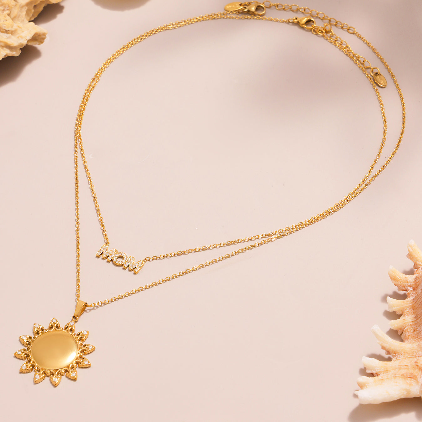 Gold necklace with sun pendant on a beige background