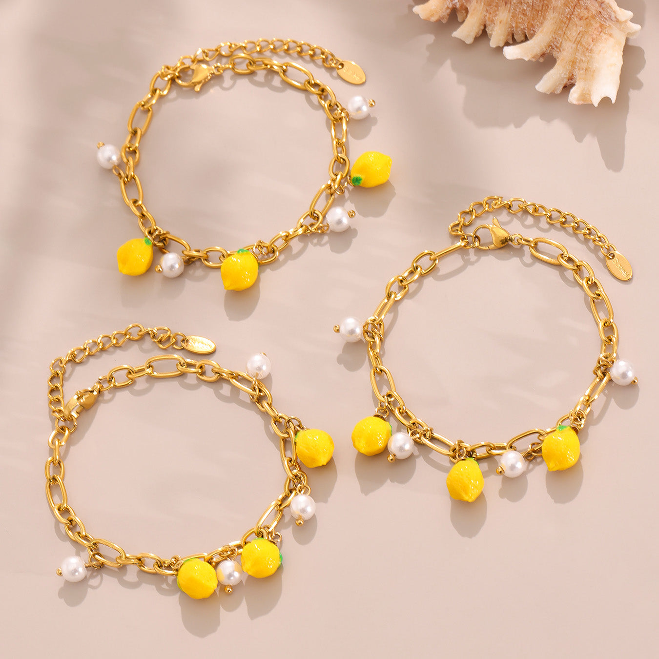 Gold anklets with yellow beads and pearls on a beige background