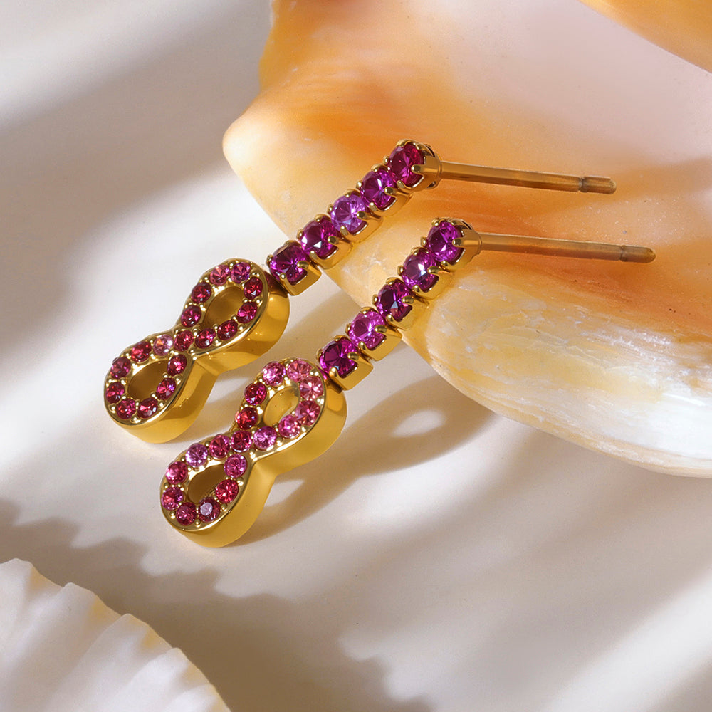 Gold earrings with pink gemstones on a shell background