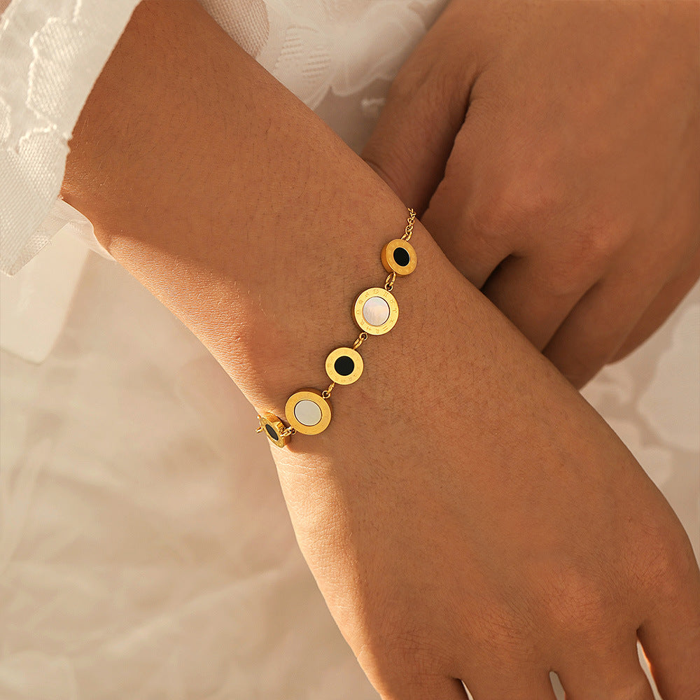 Gold tennis bracelet with shell-style circular charms on wrist against a soft background
