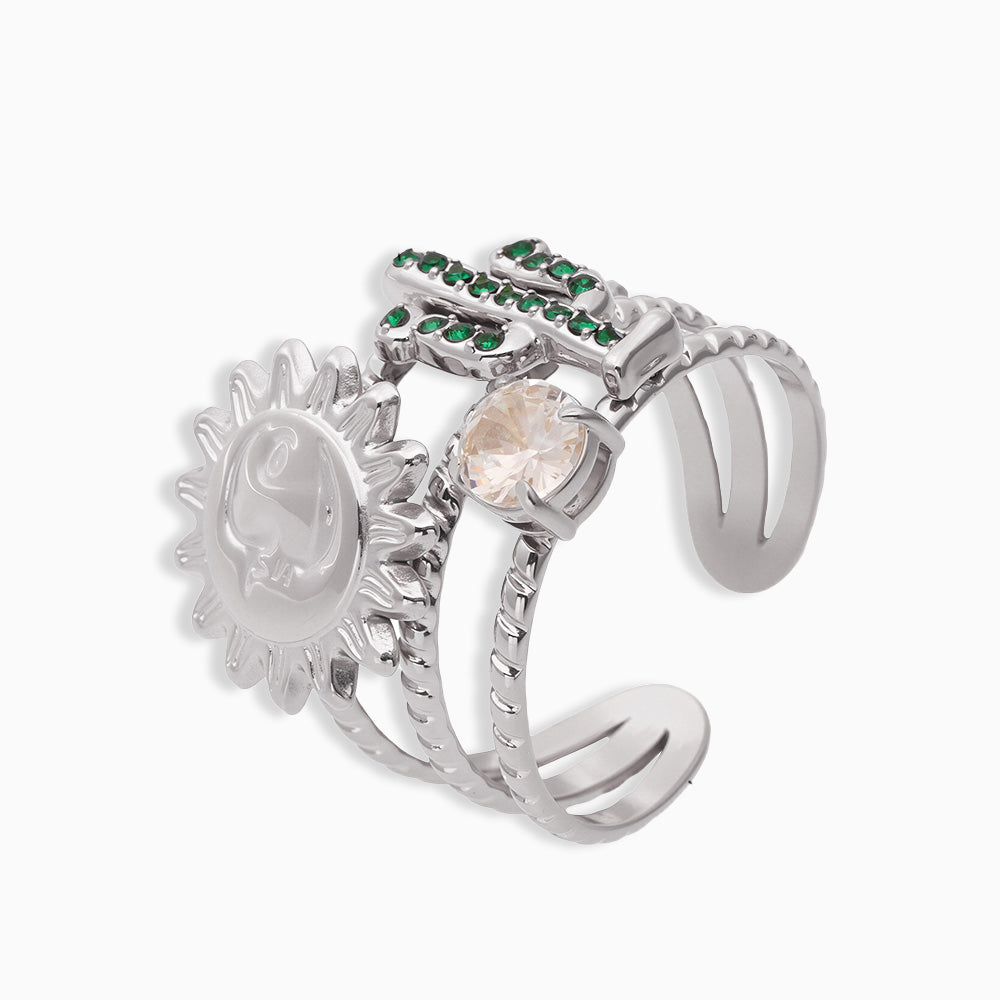 Silver chunky ring with sun design and gemstones, displayed on a light gray background.