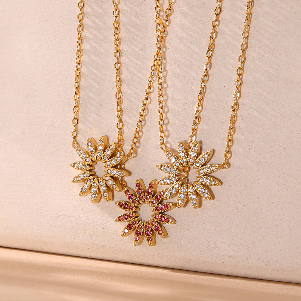 Gold sunflower necklaces with white and pink zirconia in warm light setting