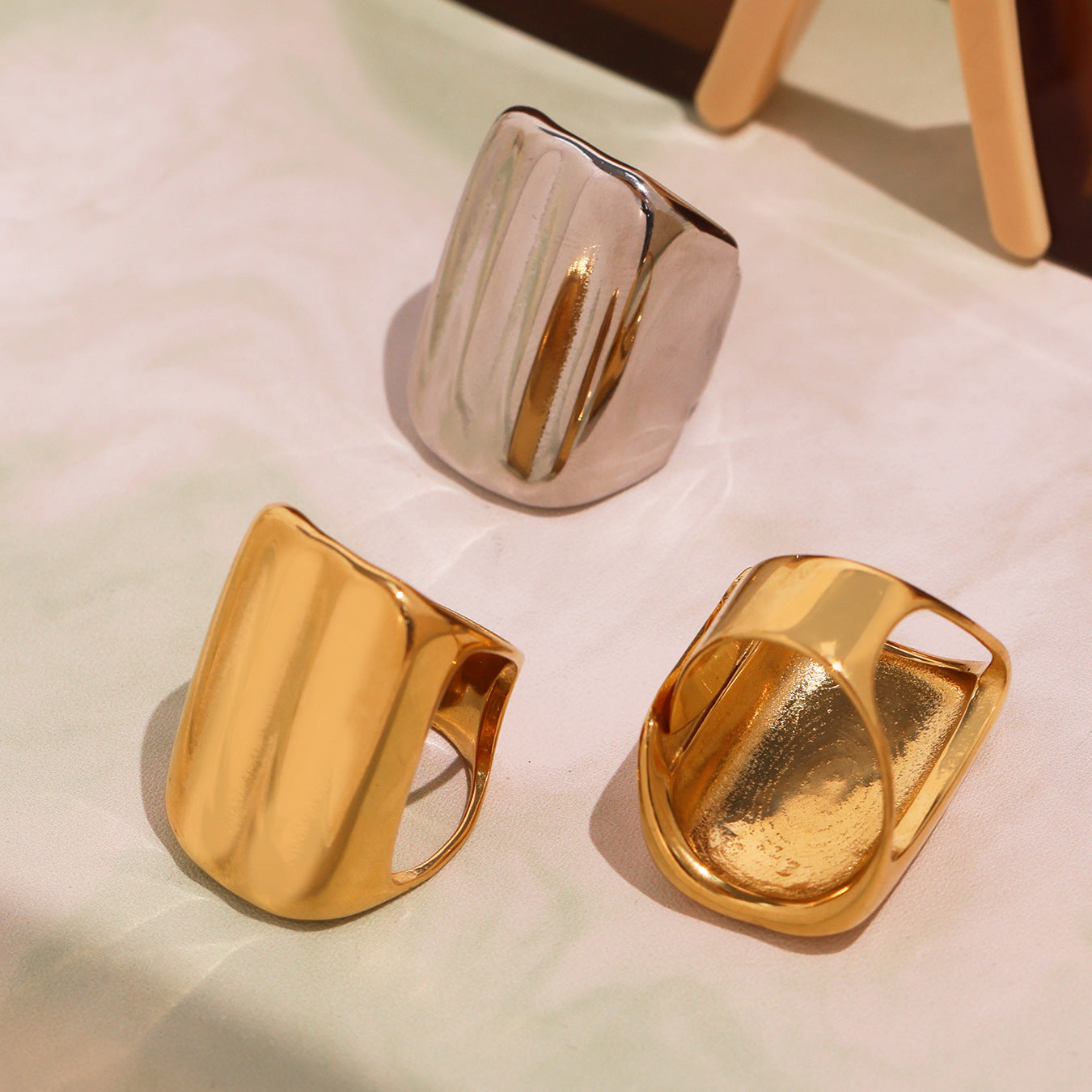 Three gold stainless steel rings arranged on a light surface, showcasing elegant design.