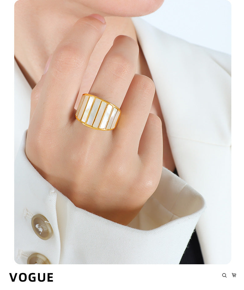 Hand wearing adjustable gold ring with VOGUE logo on white background – trendy fashion jewelry