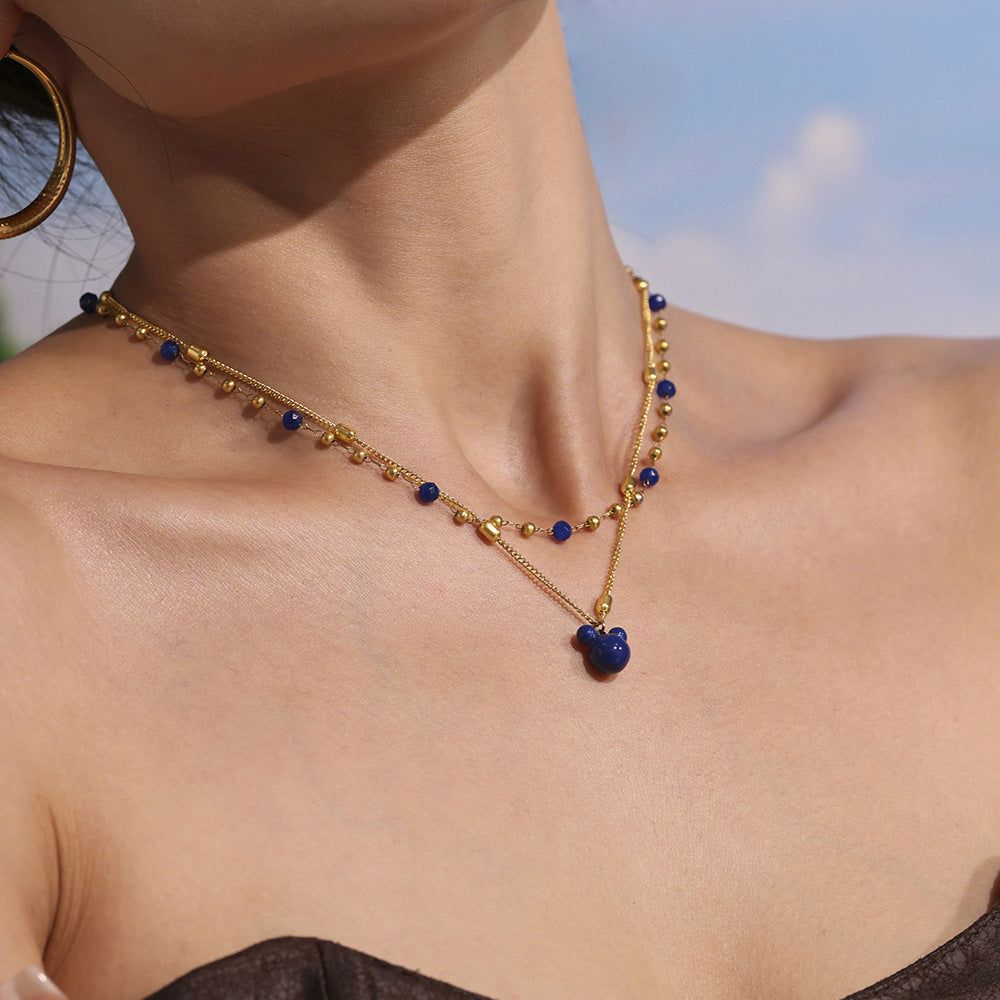 Model looking up wearing layered P705 gold natural stone necklace and gold bear charm necklace