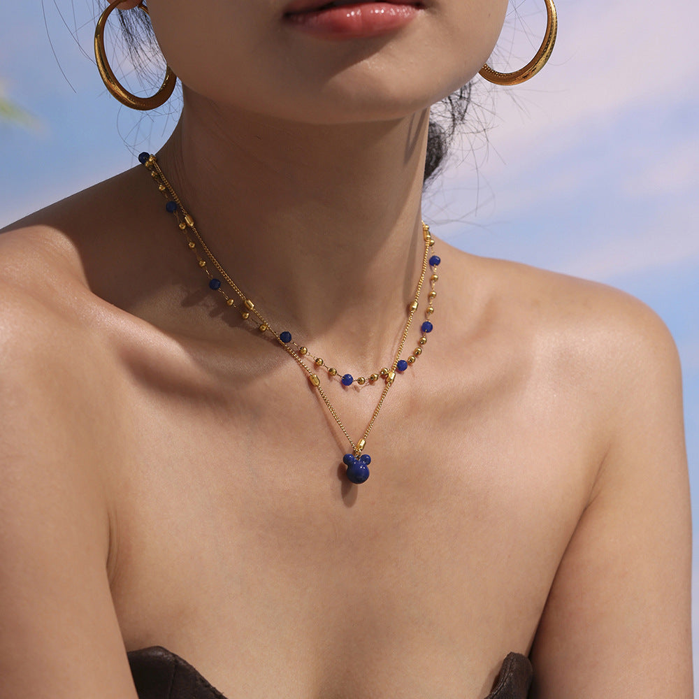 Model looking up wearing layered P705 gold natural stone necklace and gold bear charm necklace