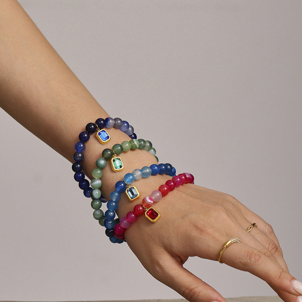 Model wearing blue, green, pink, and navy agate bracelets stacked on wrist