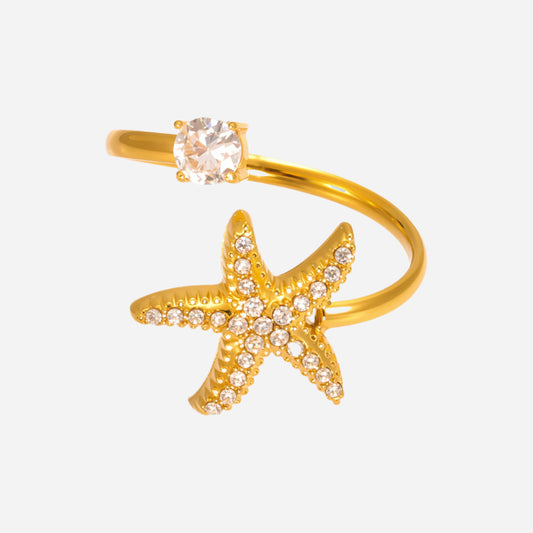 Gold starfish ring with a clear gemstone on a white background