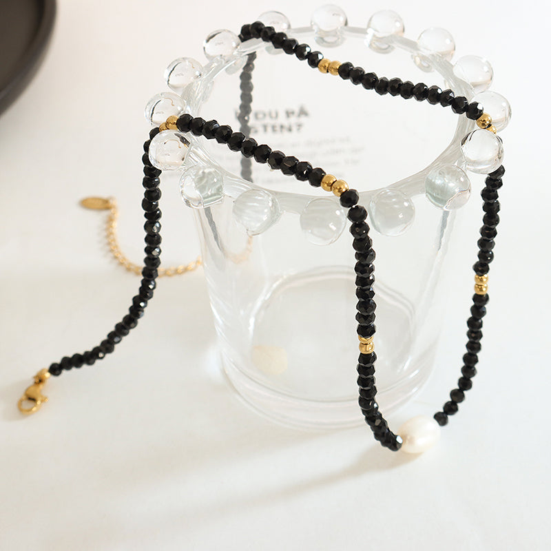 Freshwater pearl necklace casting shadows beside cup