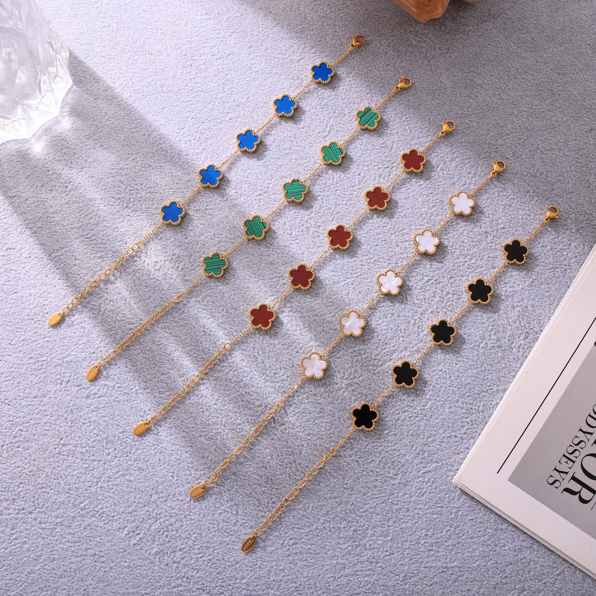  Flat lay of five gold stainless steel beaded bracelets: shell, turquoise, black, red, and blue agate