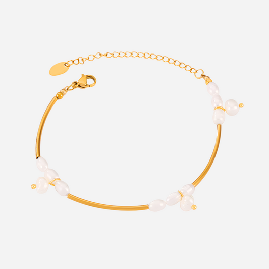 Gold bracelet with pearl beads on a light gray background