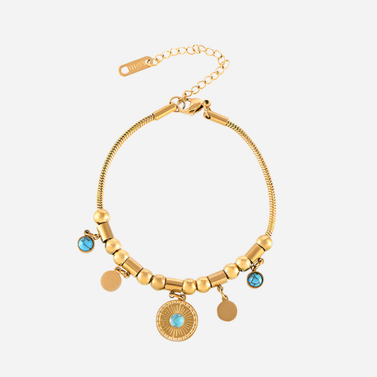 Gold bracelet with turquoise stones on a light gray background