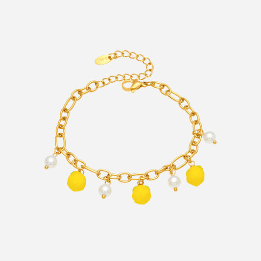 Gold bracelet with yellow charms and pearls on a white background