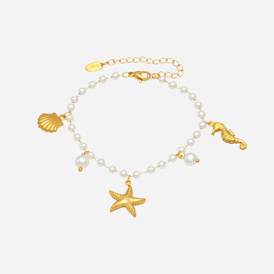 Bracelet with gold charms including a starfish, seashell, and seahorse on a white background