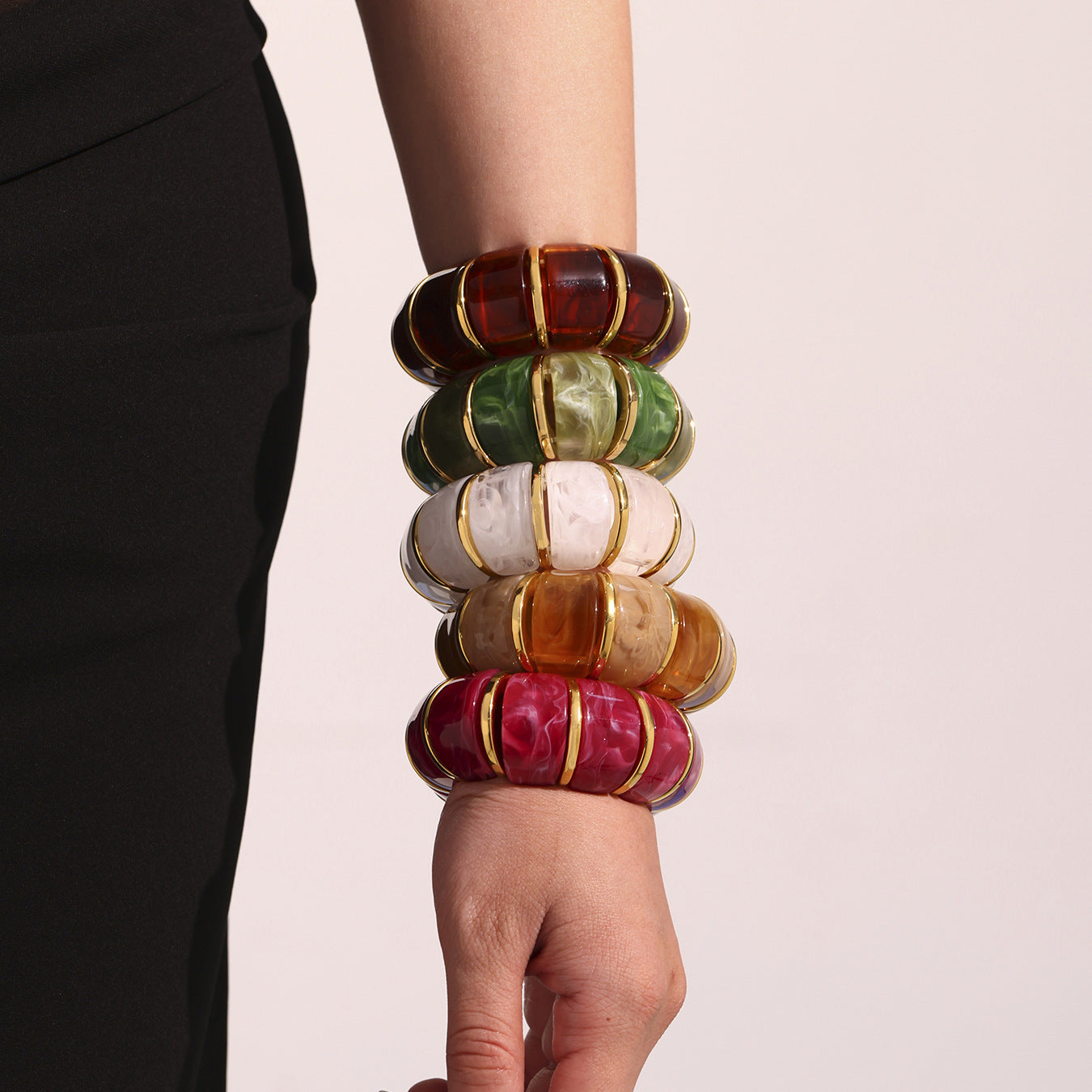 Stack of colorful bangles on a person's wrist against a plain background