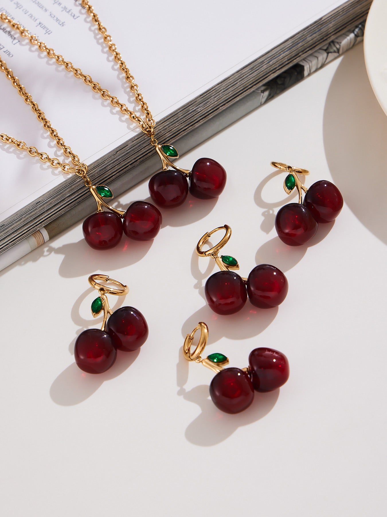 Cherry earrings and matching cherry necklace flat lay on white background