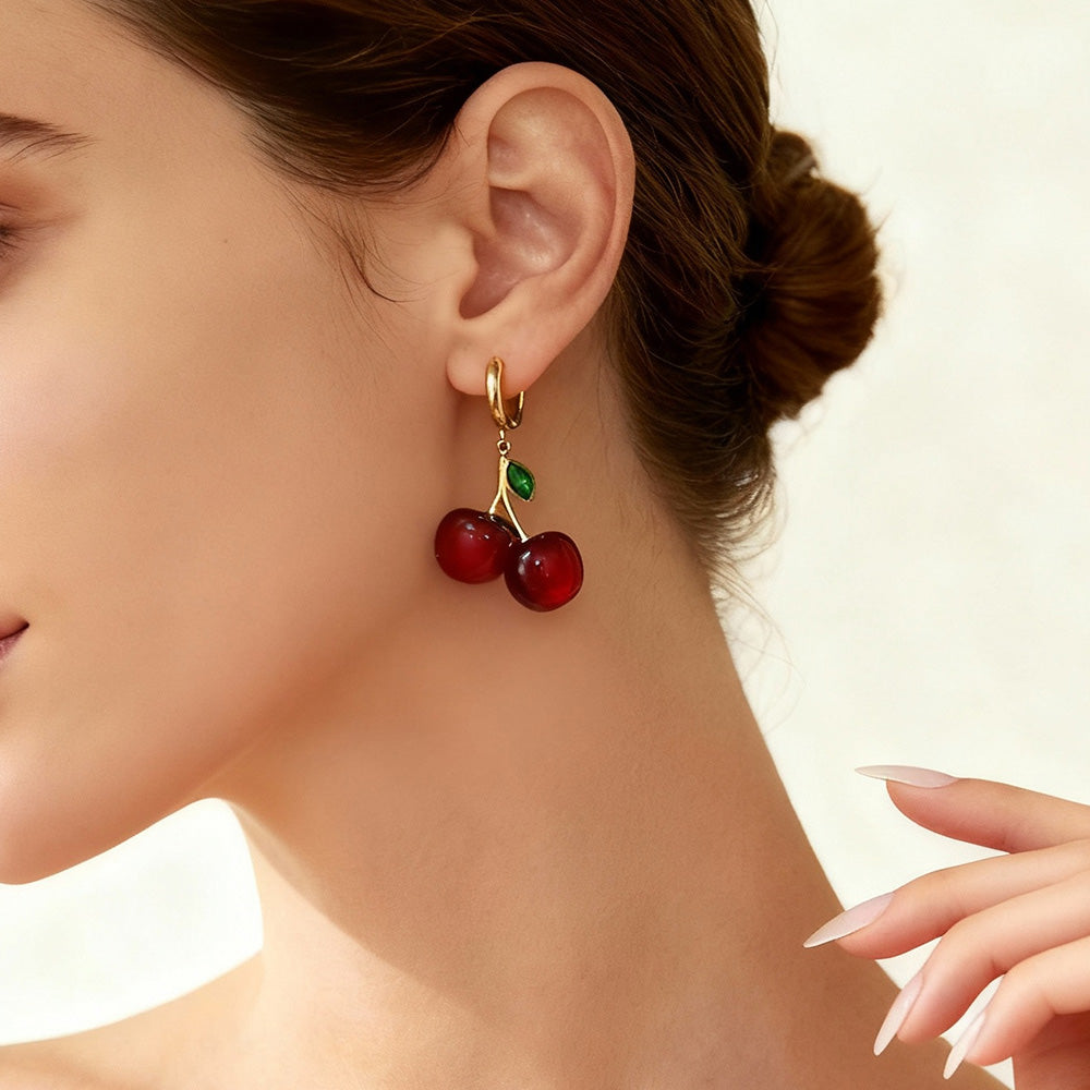 Woman styling enamel cherry earrings with elegant bun hairstyle