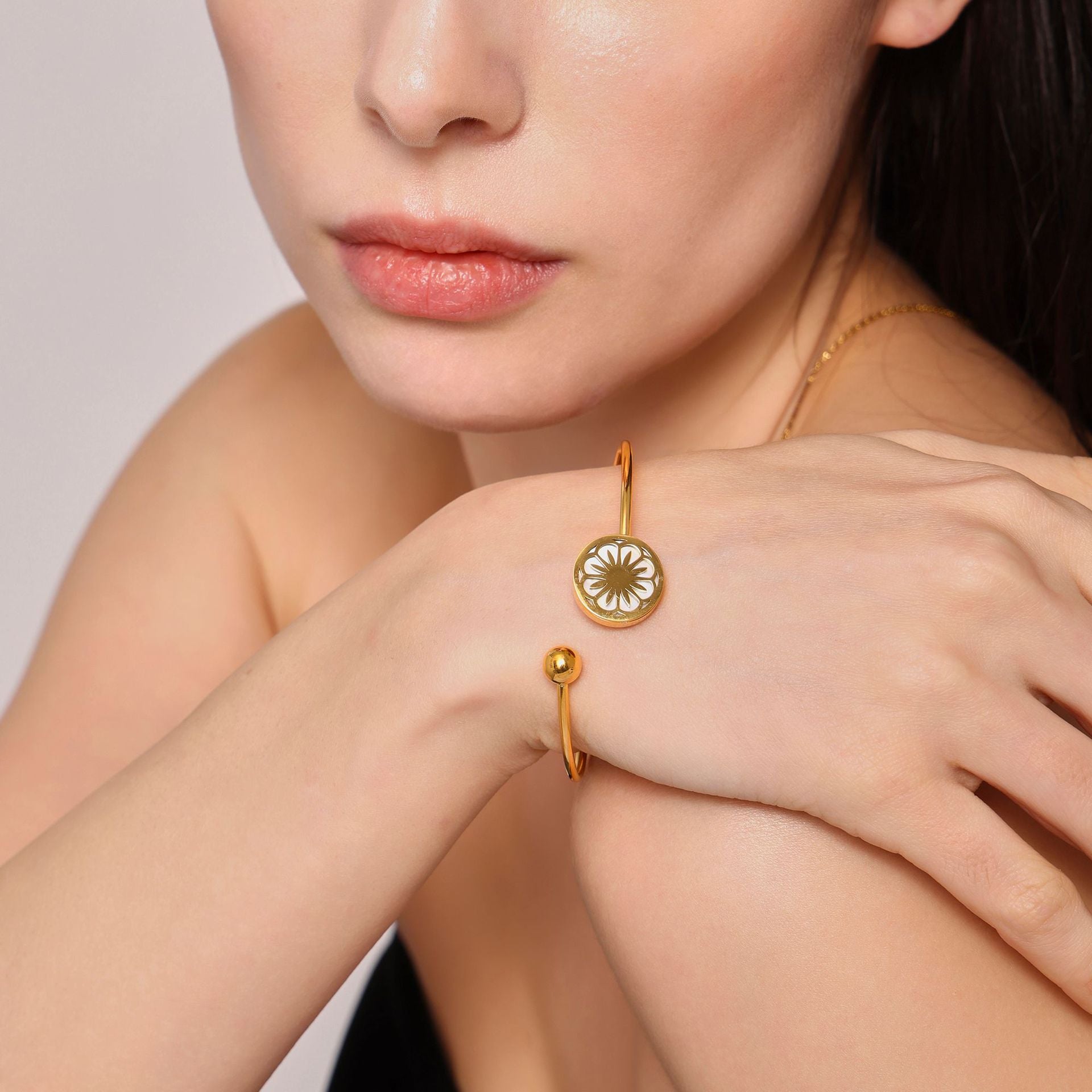  Detailed close-up of gold bracelets and necklace on woman with neutral background