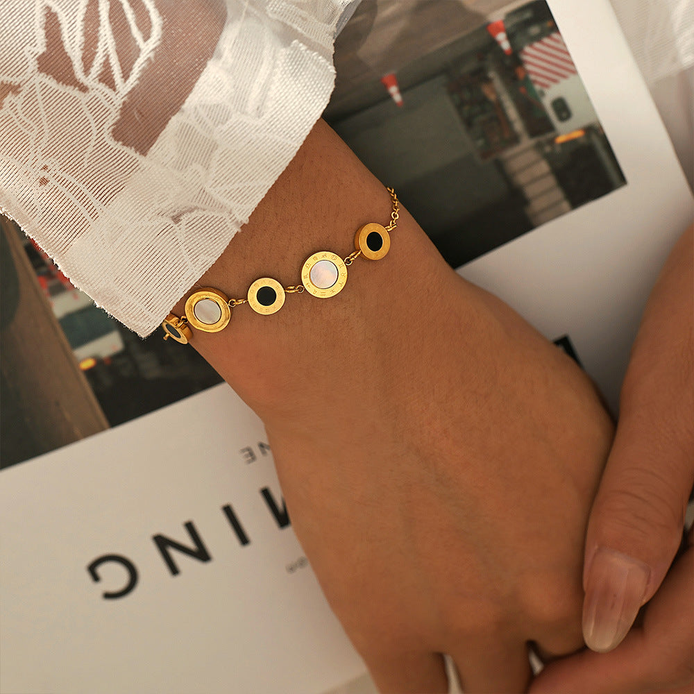 Gold circular charm tennis bracelet on wrist with soft blur background