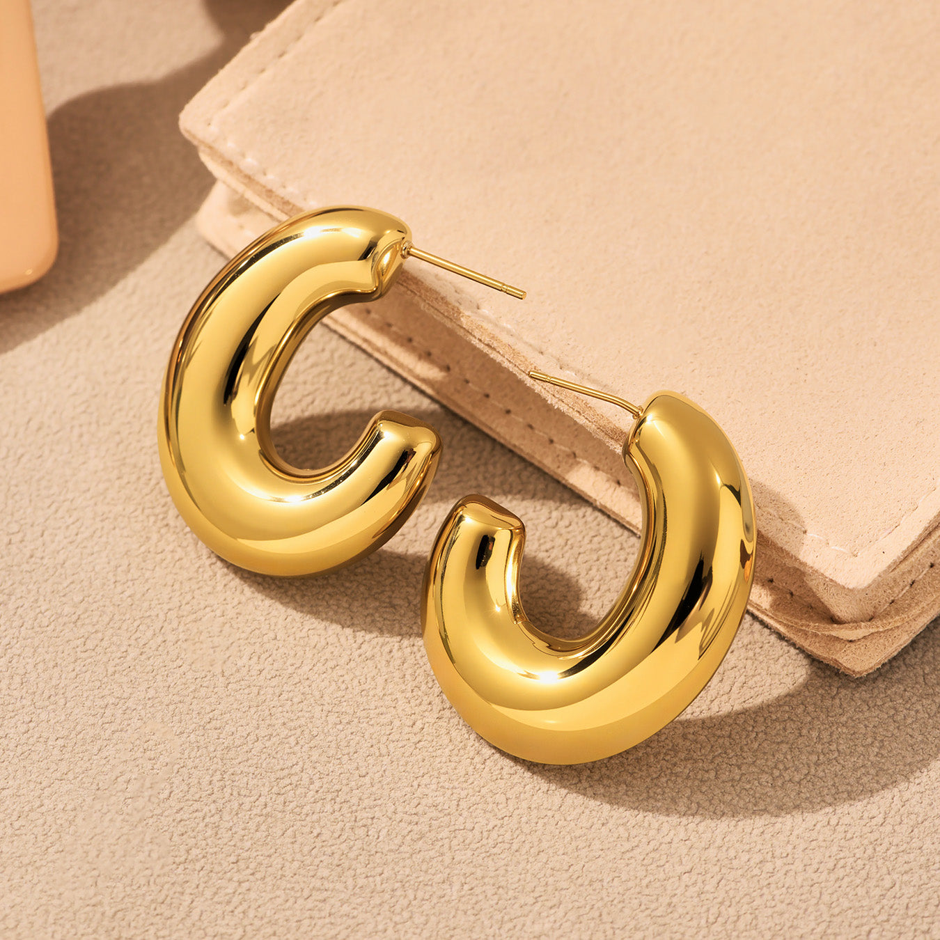 Gold hoop earrings on a beige surface