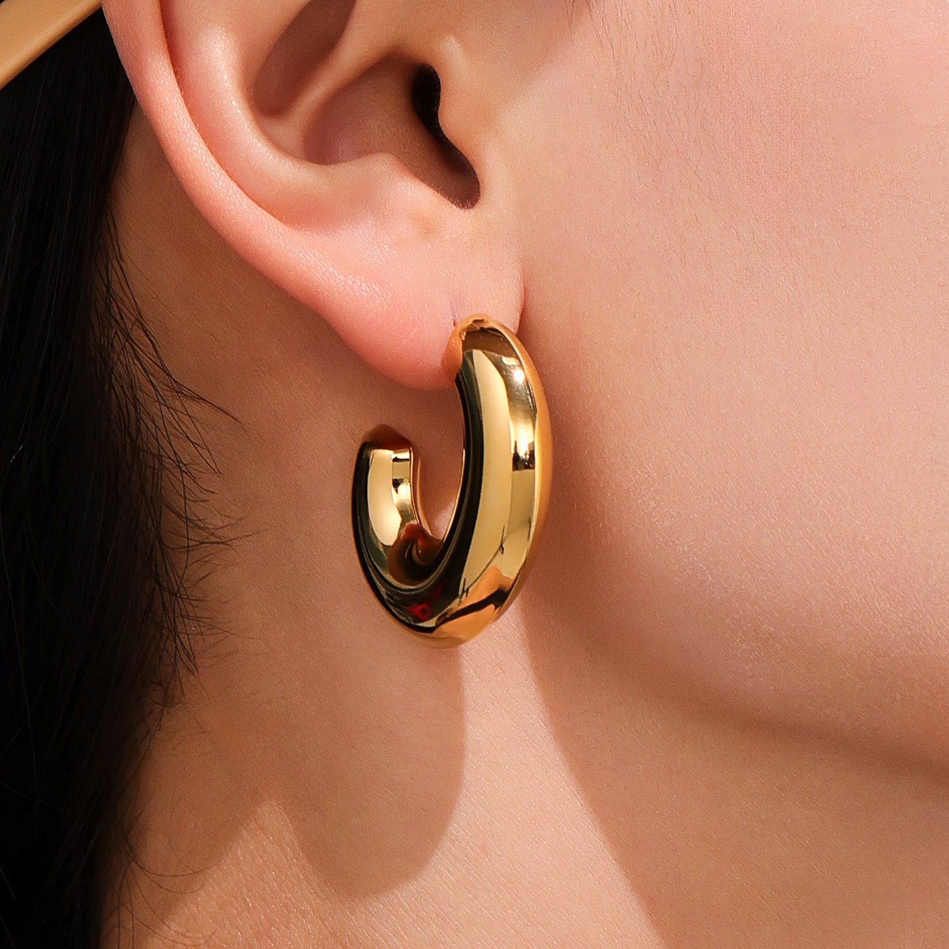 Gold hoop earring worn on a person's ear