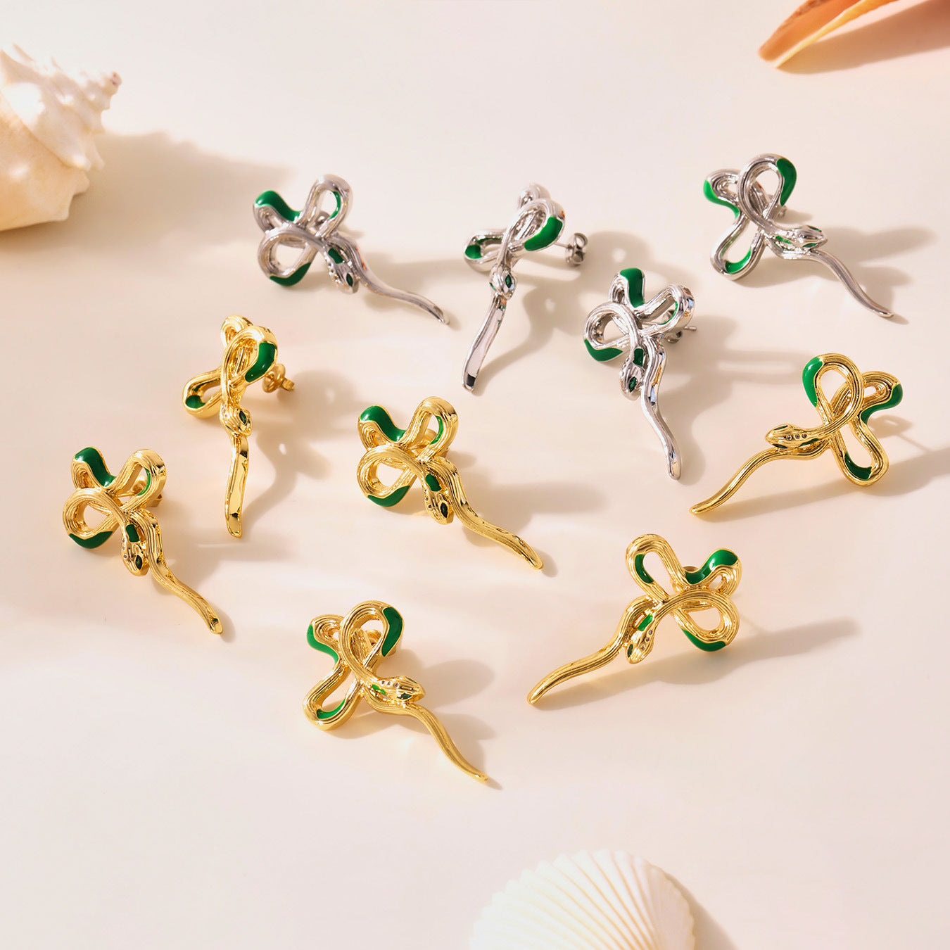 Gold and silver clover-shaped earrings with green accents on a light background