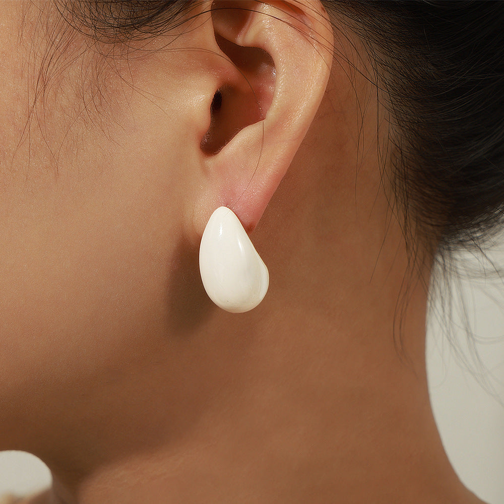 Close-up of a person wearing a white teardrop earring.