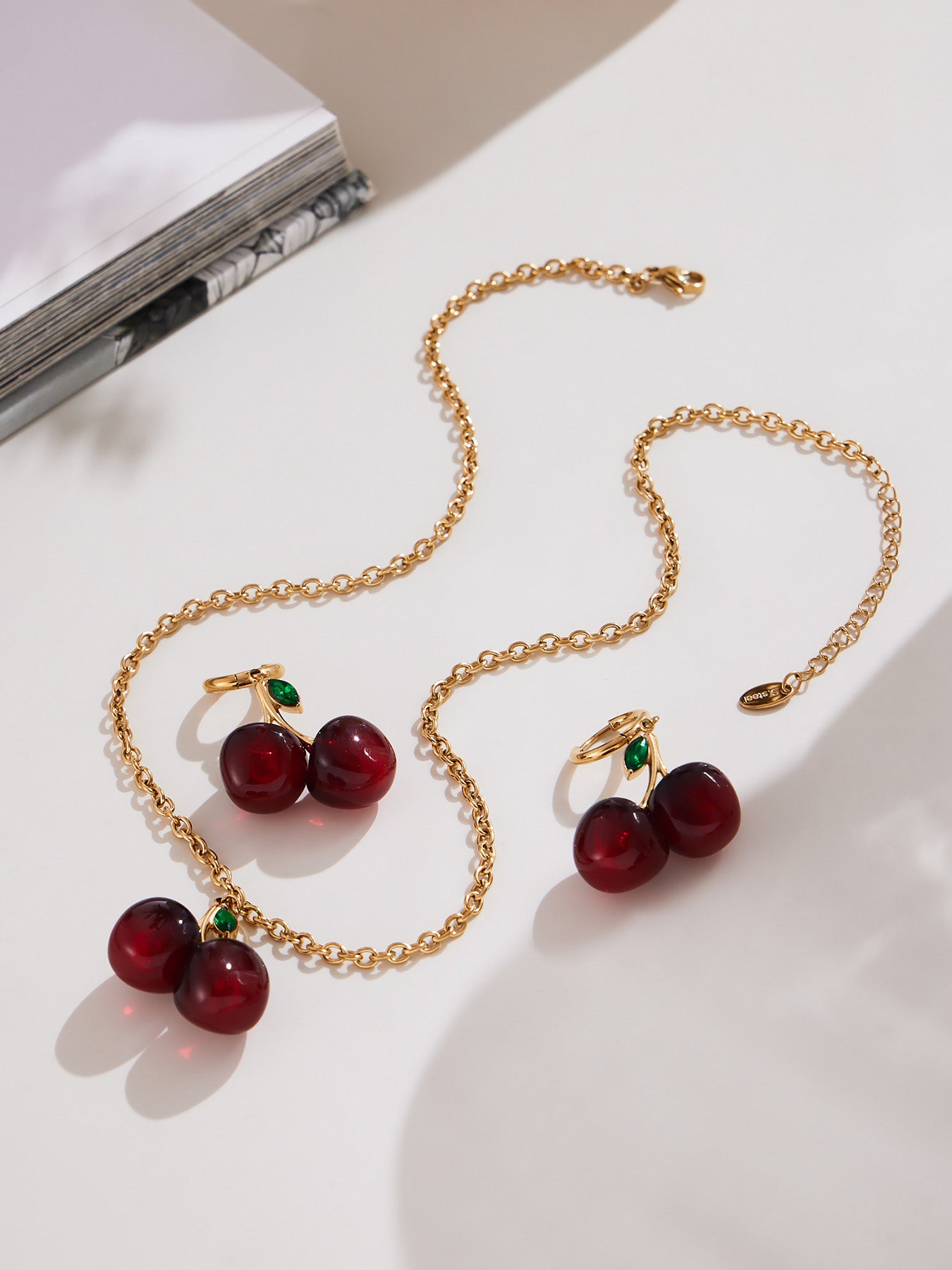 Enamel cherry hoop earrings displayed on tray with soft light