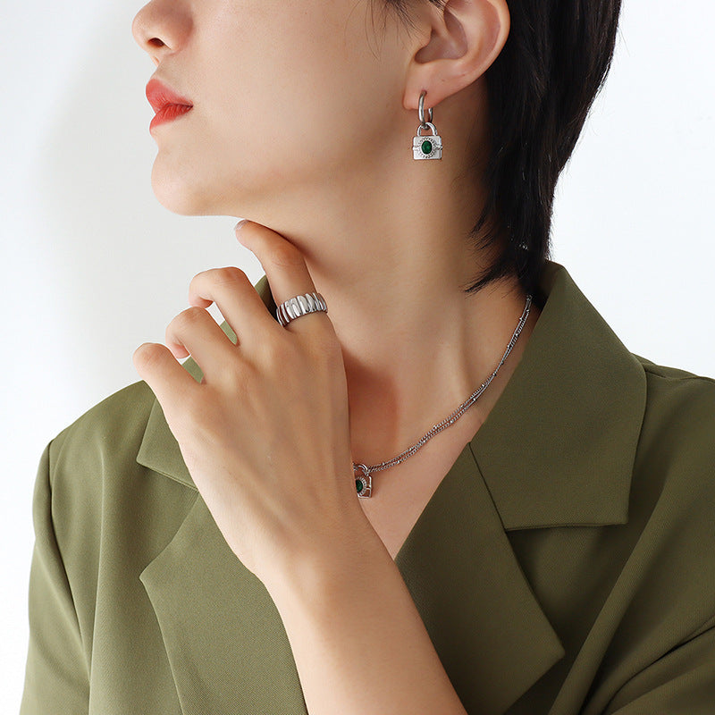 Side profile of the model showing the gold padlock lock earrings with a gemstone charm in natural soft lighting.