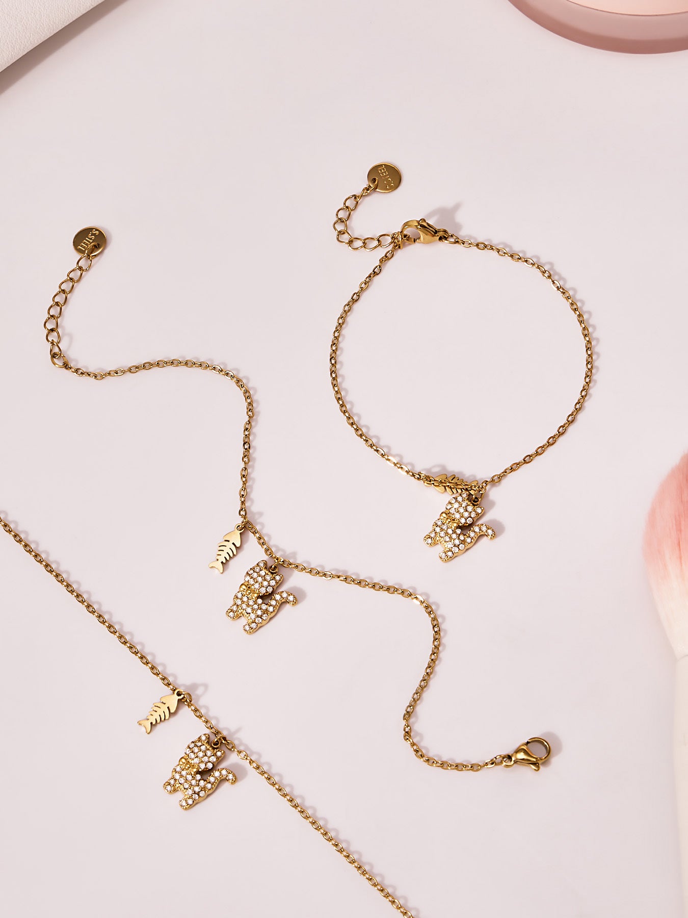 Gold cat tennis bracelet displayed flat to show the full chain, CZ cat charm, and fishbone pendant.