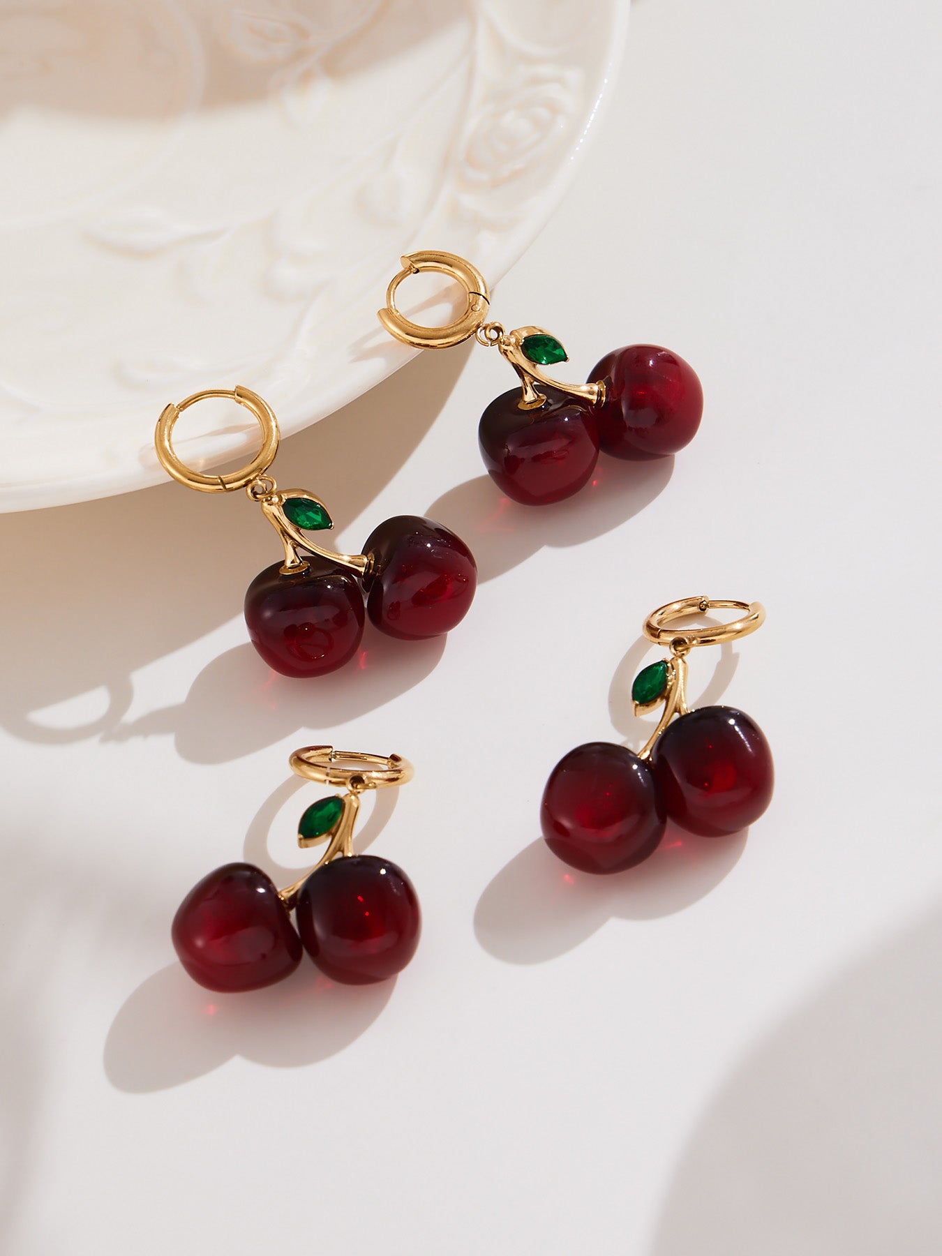 Gold cherry drop earrings styled on jewelry dish, cute vintage look
