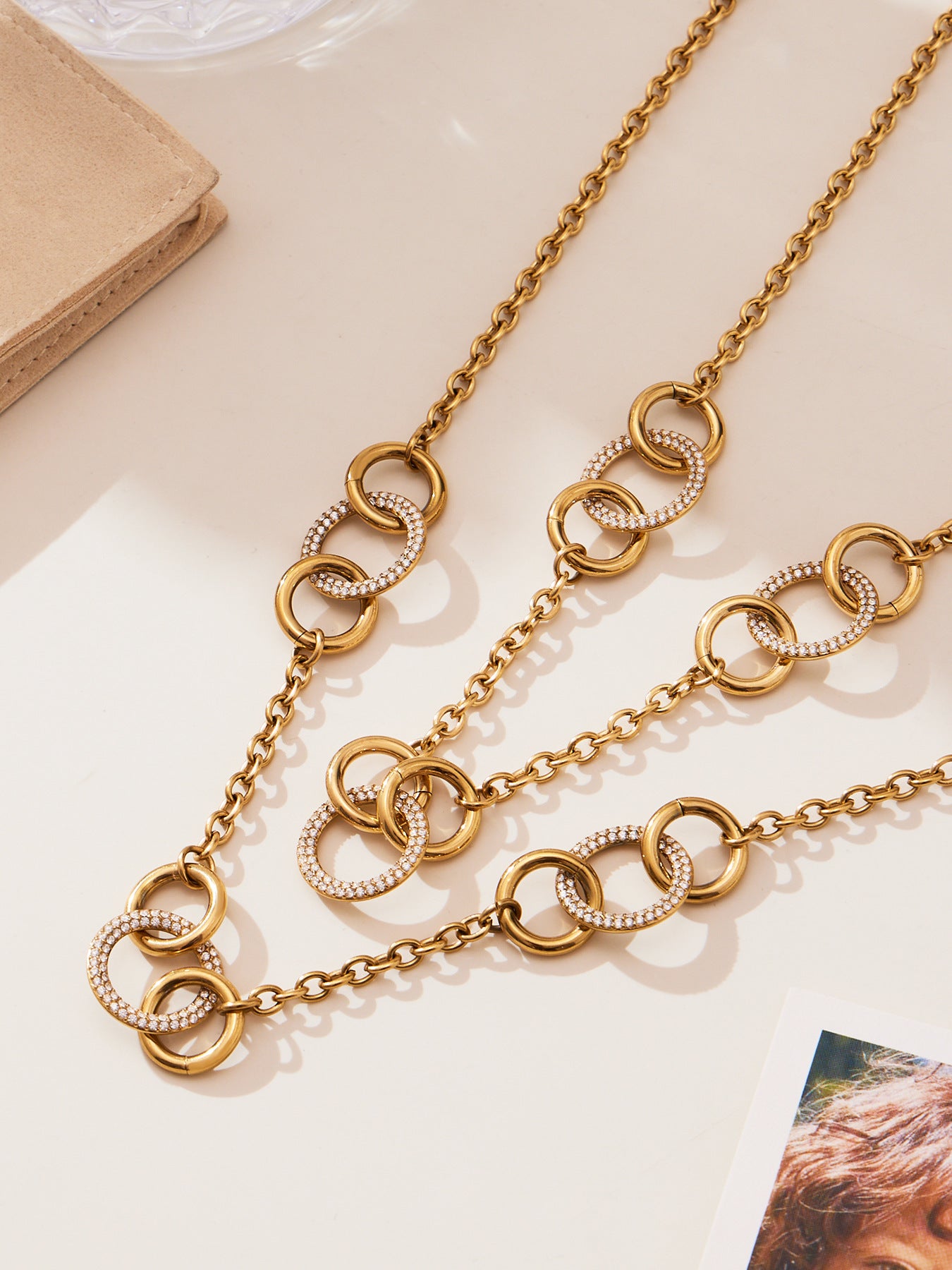 Flatlay of 18K gold interlocking circle necklace with sparkling CZ stones on neutral background