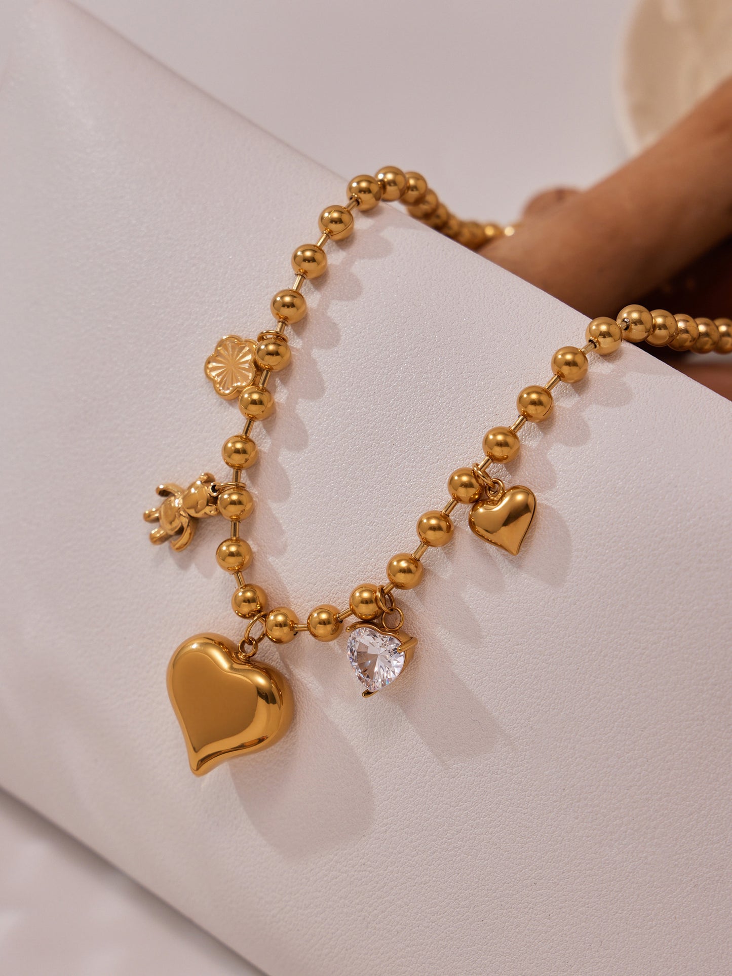 Close-up wearing gold heart charm necklace layered with bracelets, waterproof stainless steel romantic jewelry