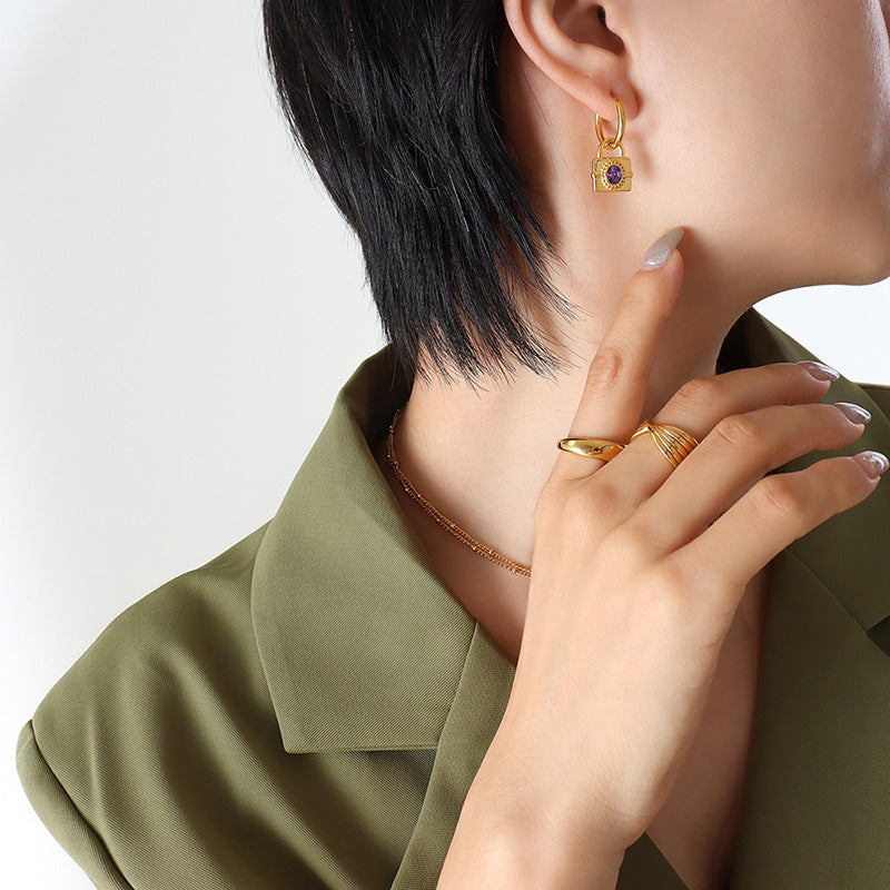 Front view of the model wearing the gold padlock earrings, highlighting the gemstone sparkle and minimalist hoop shape.