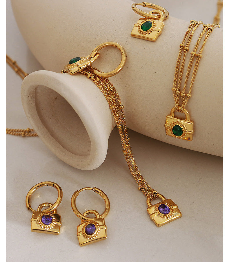 Flat lay display of gold padlock hoop earrings showing both gemstone colors and hoop details.