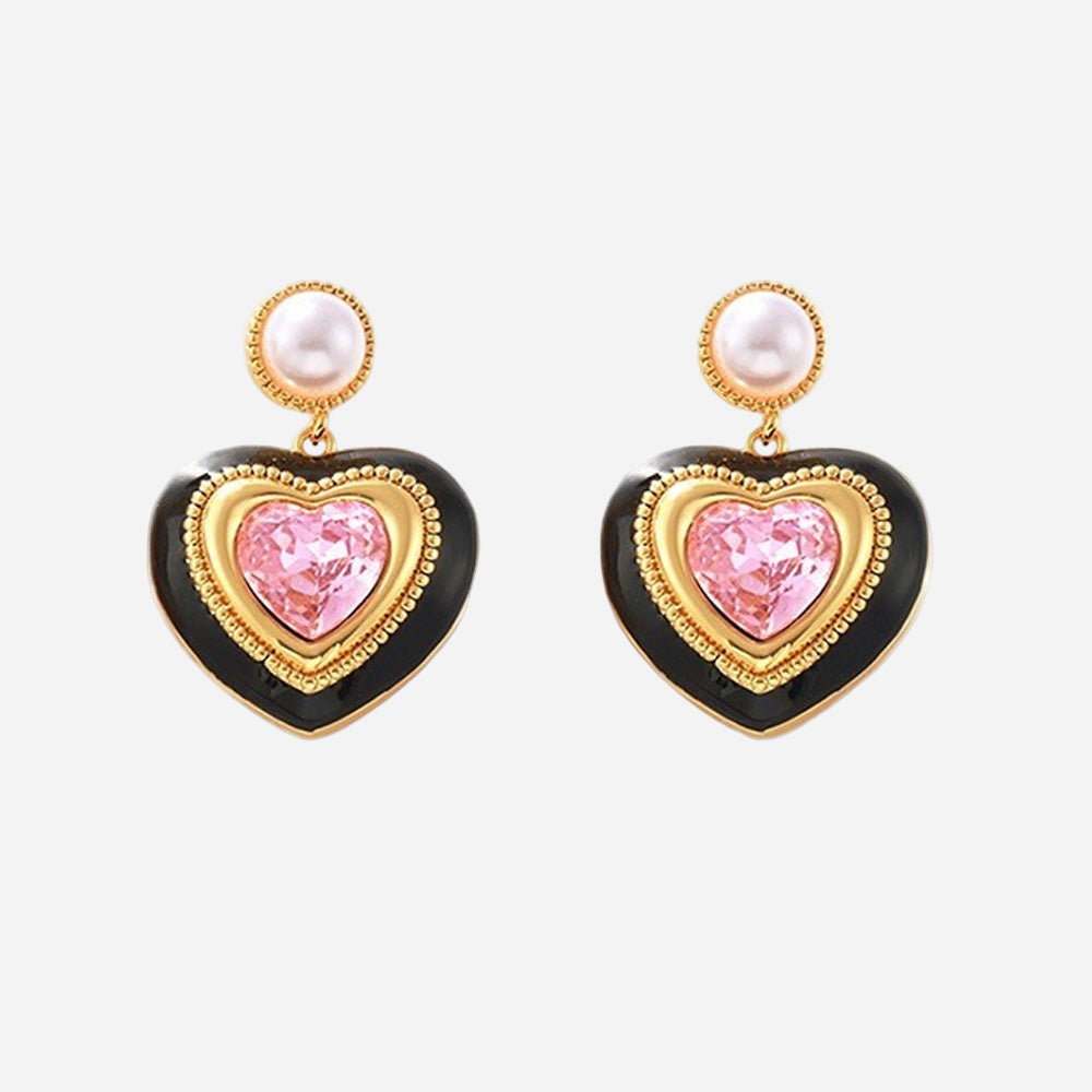 Gold heart stud earrings with pink gemstone center, black enamel border, and pearl top detail on white background