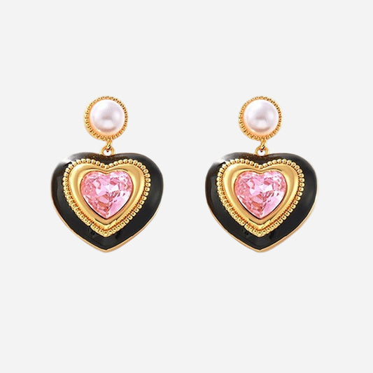 Gold heart stud earrings with pink gemstone center, black enamel border, and pearl top detail on white background