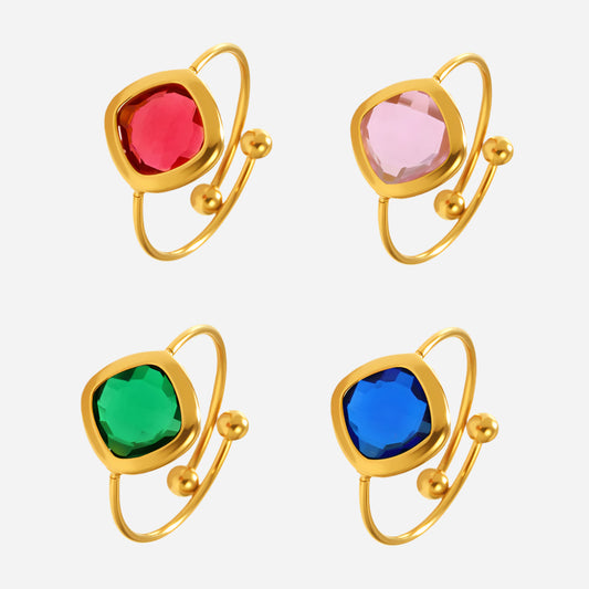 Stackable gold sea glass rings with colorful gemstones on white background