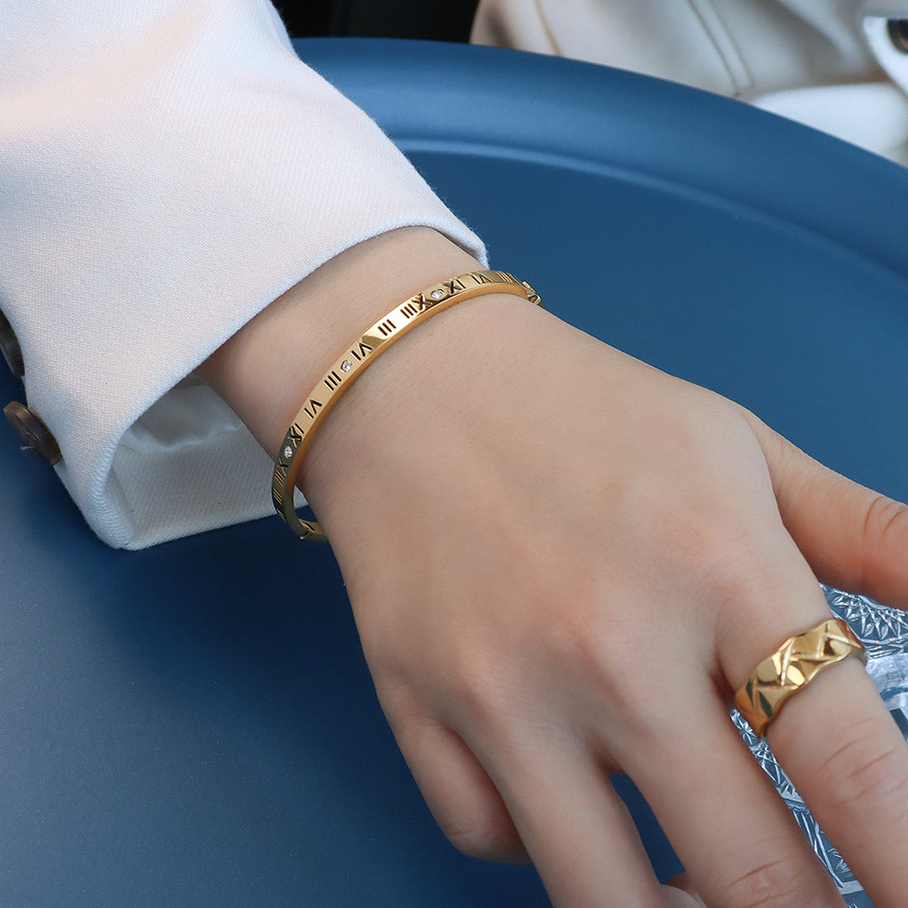  Hand with matching gold ring and slim charm bracelet on blue background