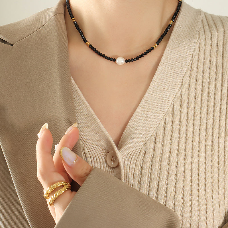 Woman wearing black glass bead necklace with freshwater pearl pendant