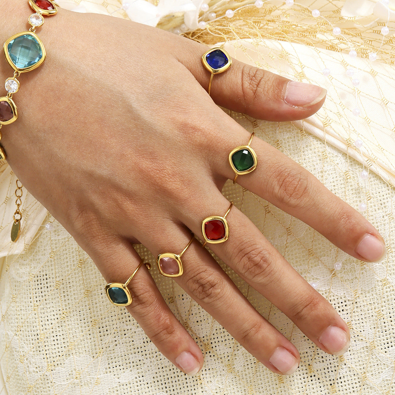 Hand wearing layered gold sea glass rings with colorful Czech gemstones