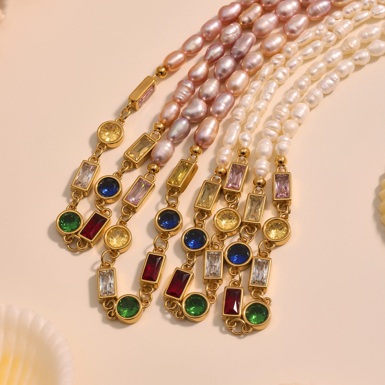 Pearl necklaces with gold and gemstone pendants on a beige background